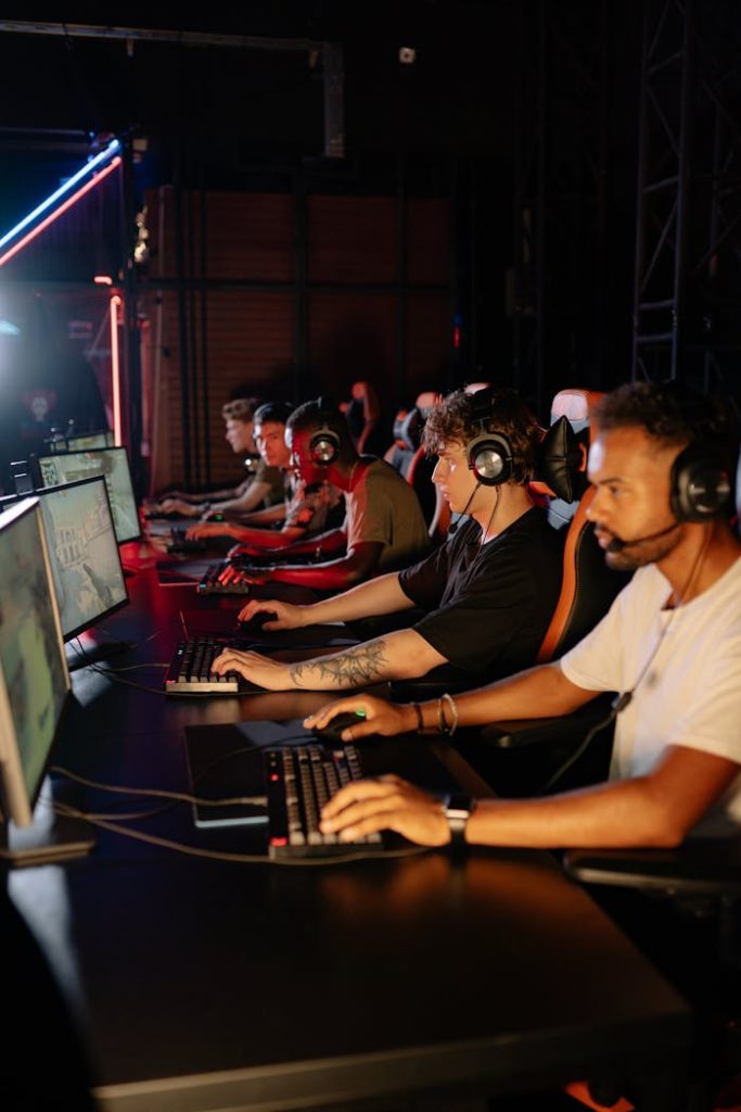 Focused gamers on computers in a dimly lit room during an intense eSports tournament.